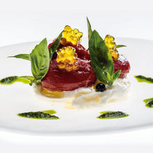 Cargar imagen en el visor de la galería, Plato gourmet con esferas doradas, hojas verdes y aceitunas negras sobre base cremosa.