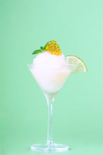Cargar imagen en el visor de la galería, Copa de cóctel con sorbete blanco, decorada con caviar amarillo y hojas de menta, y una rodaja de lima.